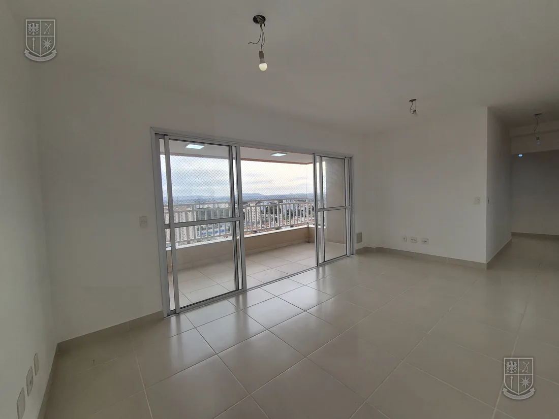 Sala vazia vista de outro ângulo, com a porta de vidro da varanda ao fundo.
